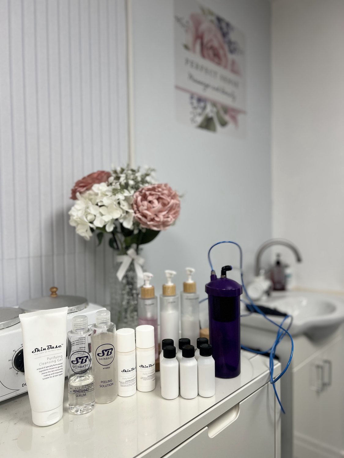 A corner of the treatment room with flowers, products and the Perfect Sense print
