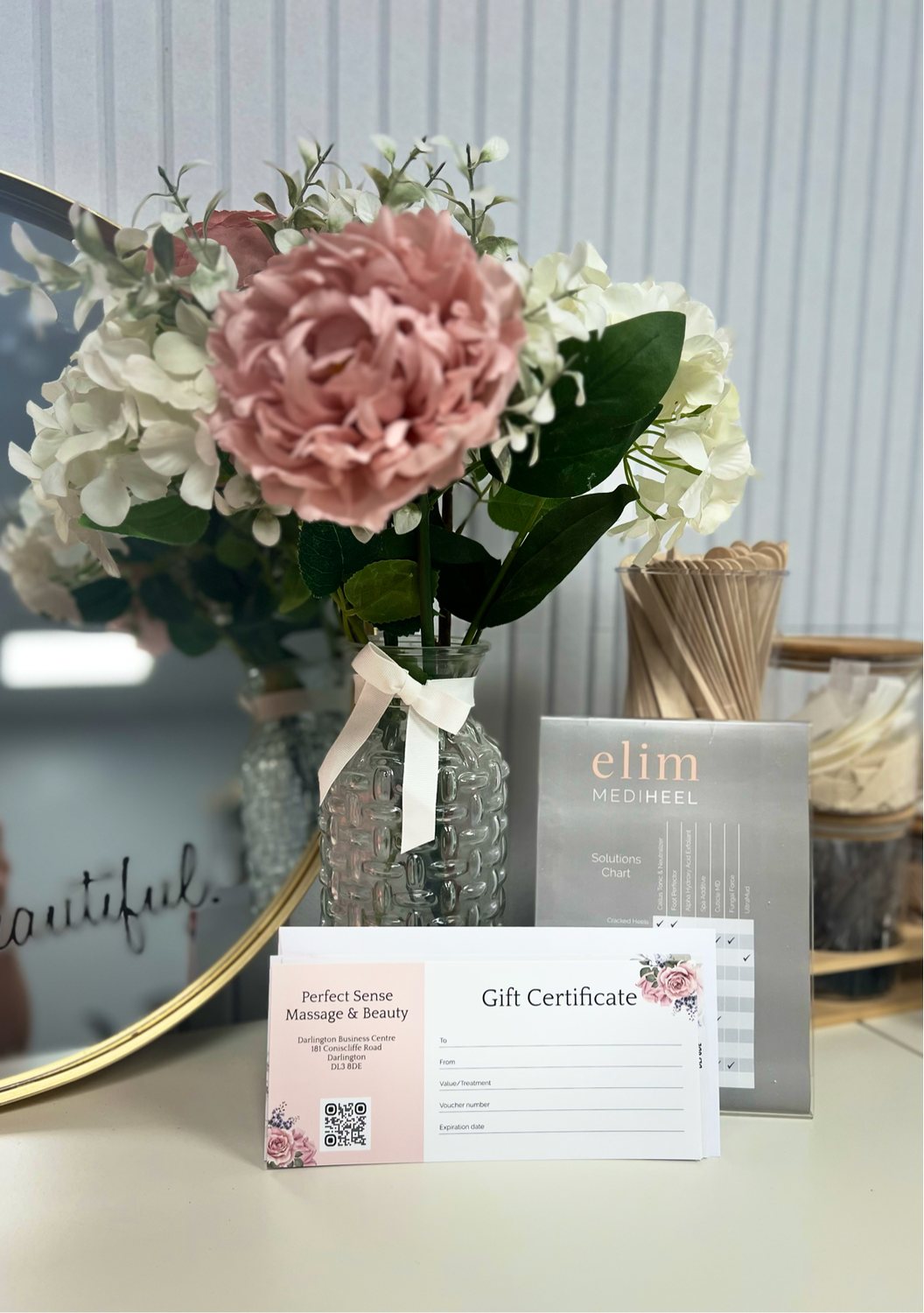Flowers in a vase with Perfect Sense gift certificates in front